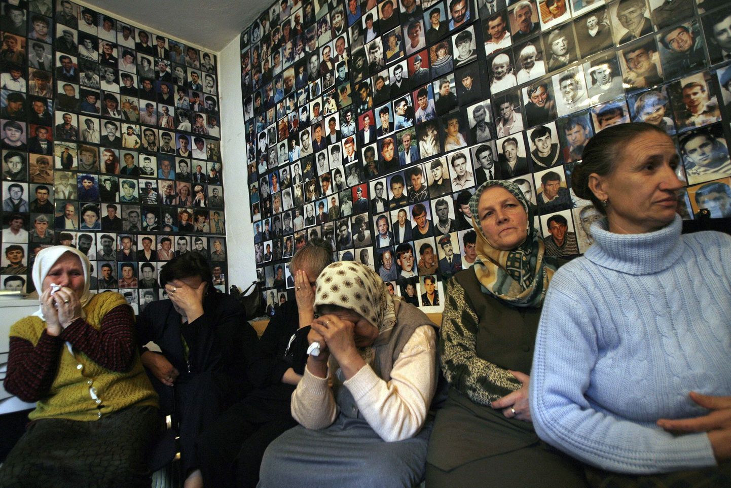 Srebrenica veresaunas tapetute pereliikmed oma lähedaste piltidega kaetud seina ees