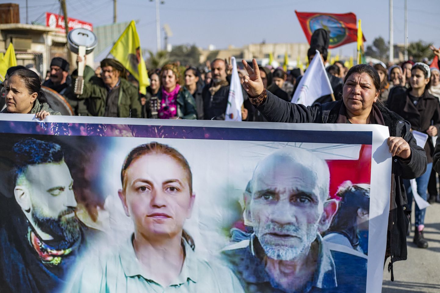 Сирийские курды держат плакат с фотографиями трех жертв во время акции протеста в городе Хасаке.
