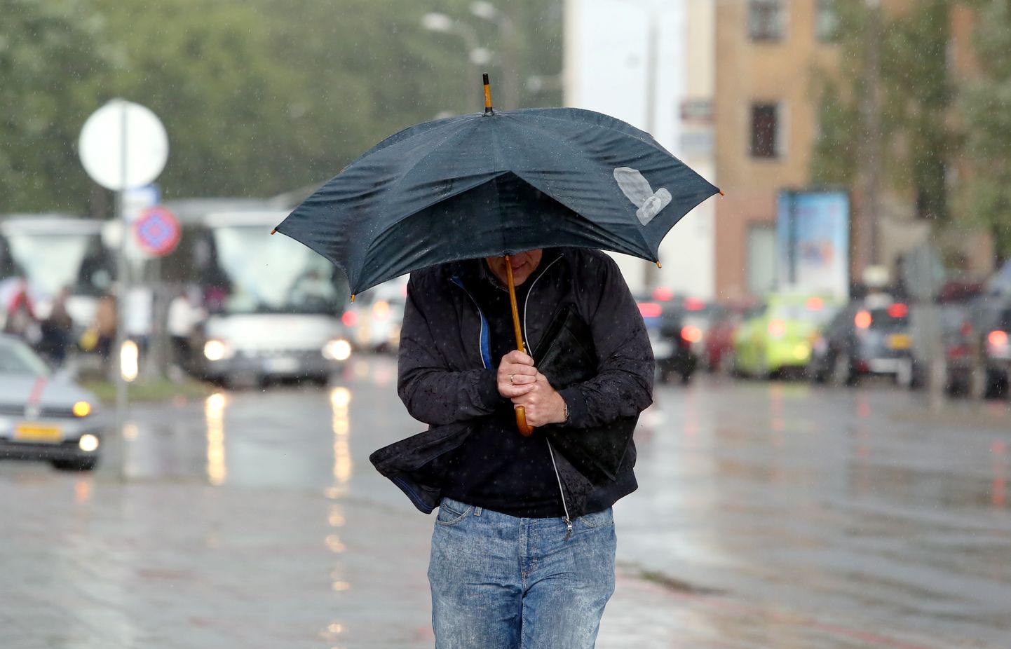 Vīrietis ar lietussargu negaisa laikā.