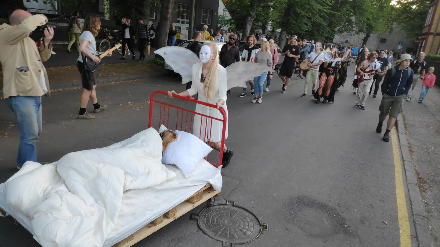 Pärnu kunstinädala etendusel sammusid taidluskunstnikud rongkäigus kunstike majast loovlinnakusse, veeretades tänaval voodit ja paisates õhku värvilisi tossupahvakuid.