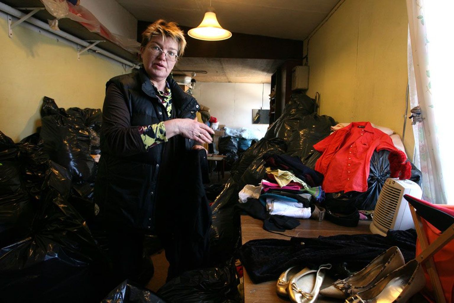 Tallinna Paide tänava Uuskasutuskeskuse poe juhataja Külli Toom sorteerib annetatud rõivahunnikuid. Paraku on korralike rõivaste seas pahatihti ka katkisi ja määrdunud asju.