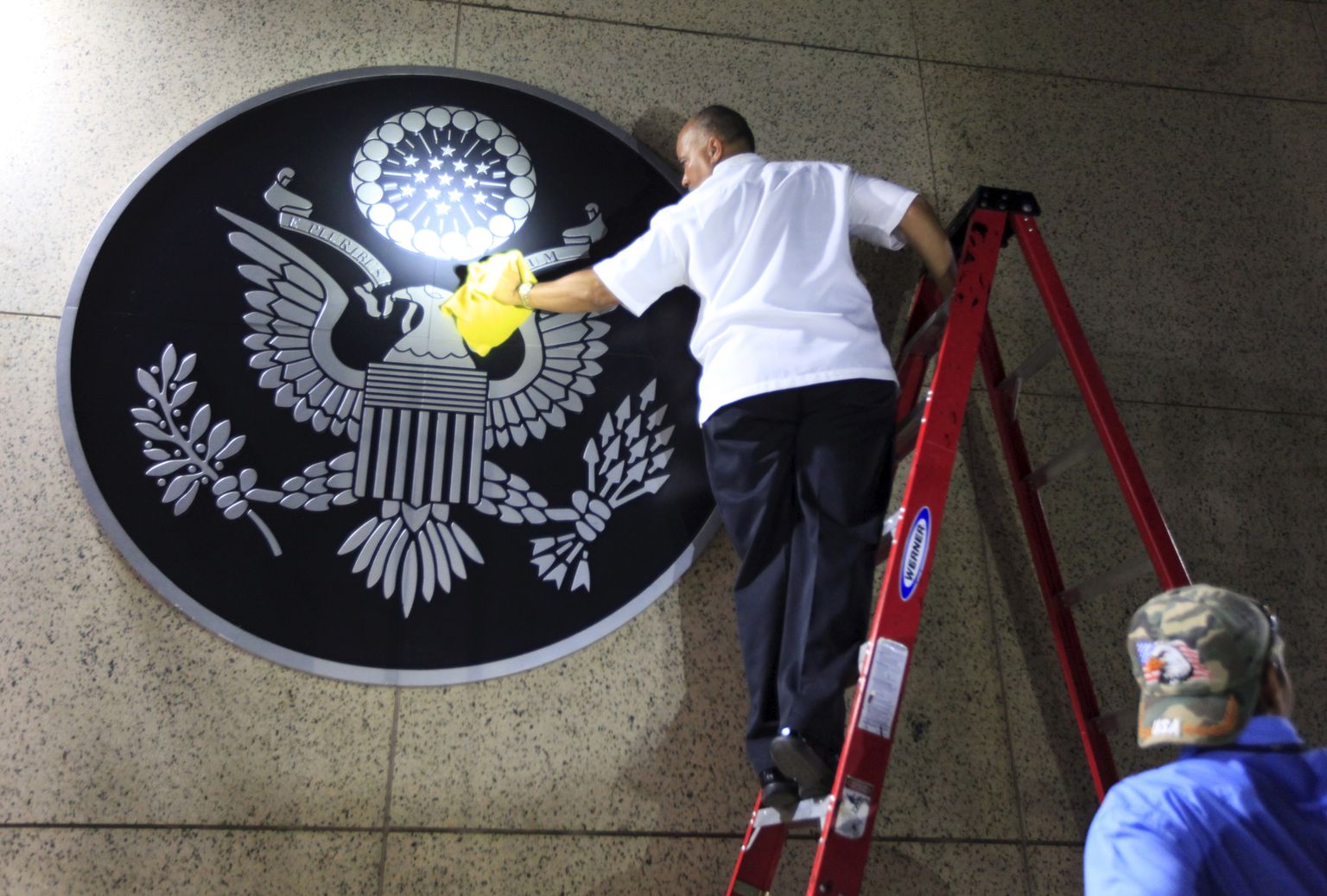 Töötaja puhastamas Ameerika Ühendriikide vappi saatkonna sissepääsu juures.