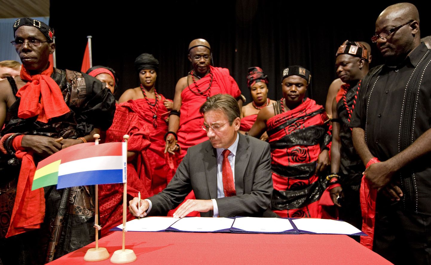 Hollandi välisminister Maxime Verhagen (keskel) kirjutamas alla dokumentidele, mille alusel tagastatakse Ghanasse kunagise hõimujuhi äraraiutud pea