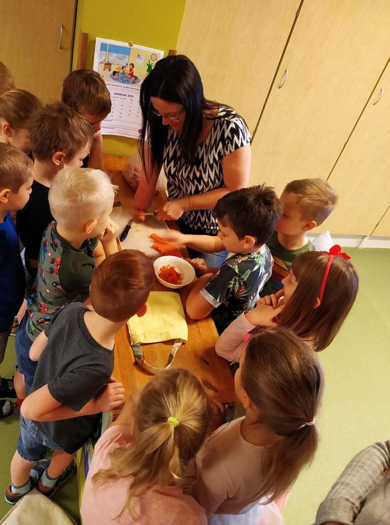 Элери Ланг показывает воспитанникам детского сада "Солнечный зайчик", как она режет морковь при помощи одной руки.