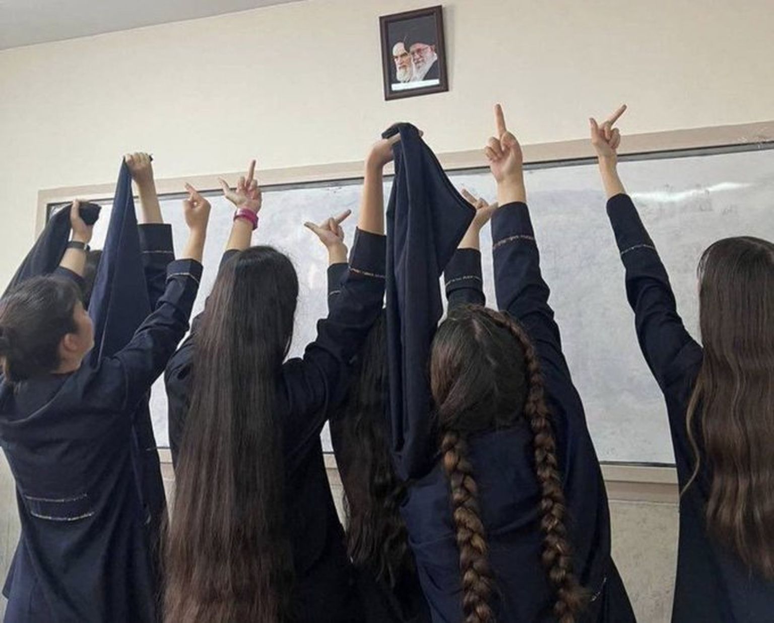 Iraani tüdrukud ajatolla Khamenei fotole keskmist sõrme näitamas.