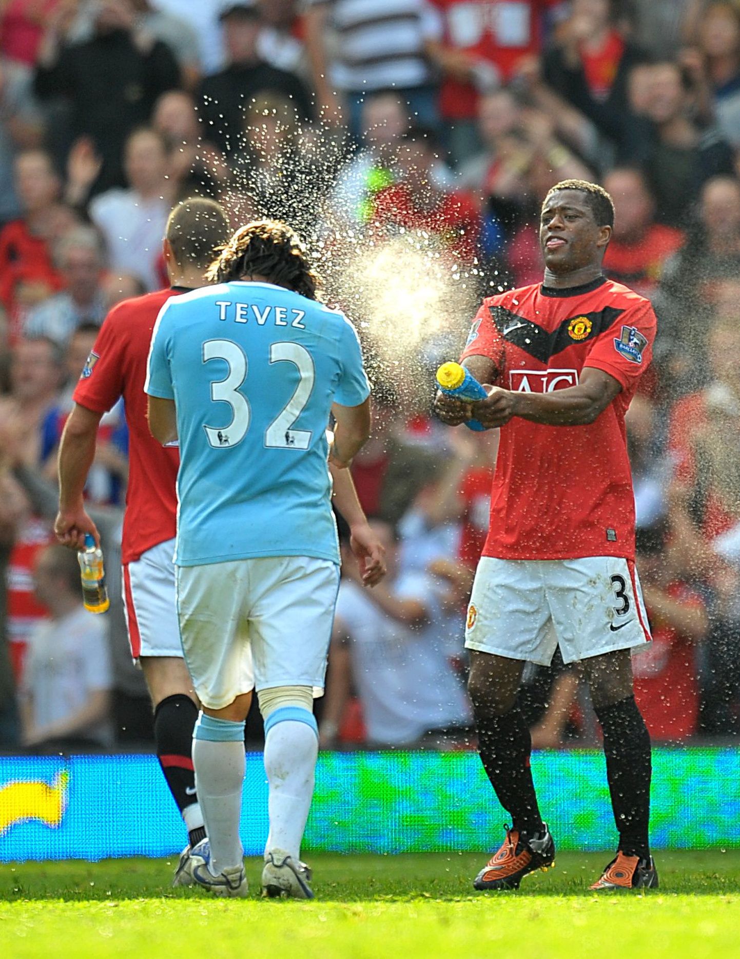 Manchester Unitedi mängija Patrice Evra pritsib endise meeskonnakaaslase Carlos Tevezi suunas vett.