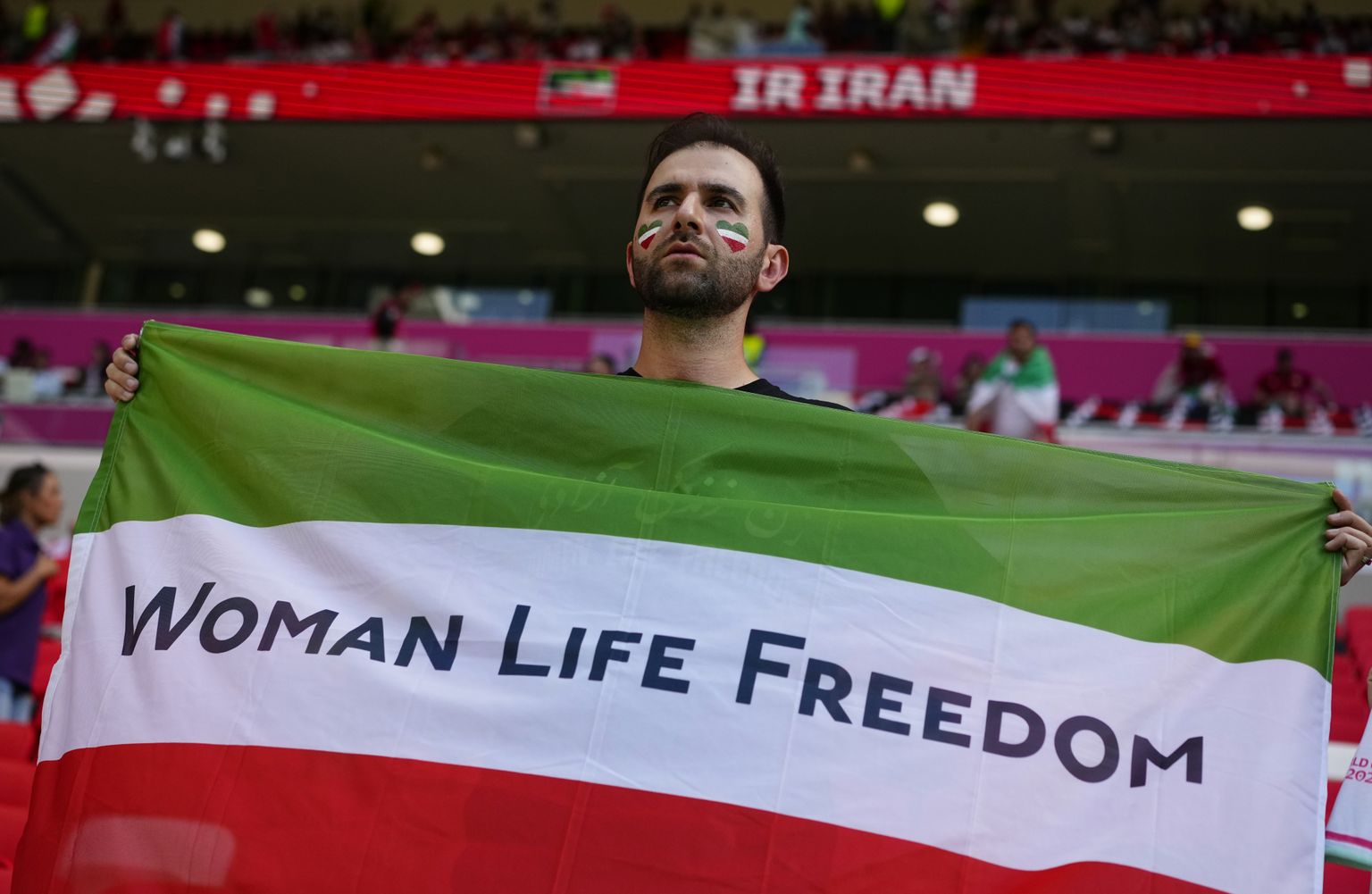 Futbola līdzjutējs tur rokās Irānas karogu un aicina iestāties par sieviešu tiesībām