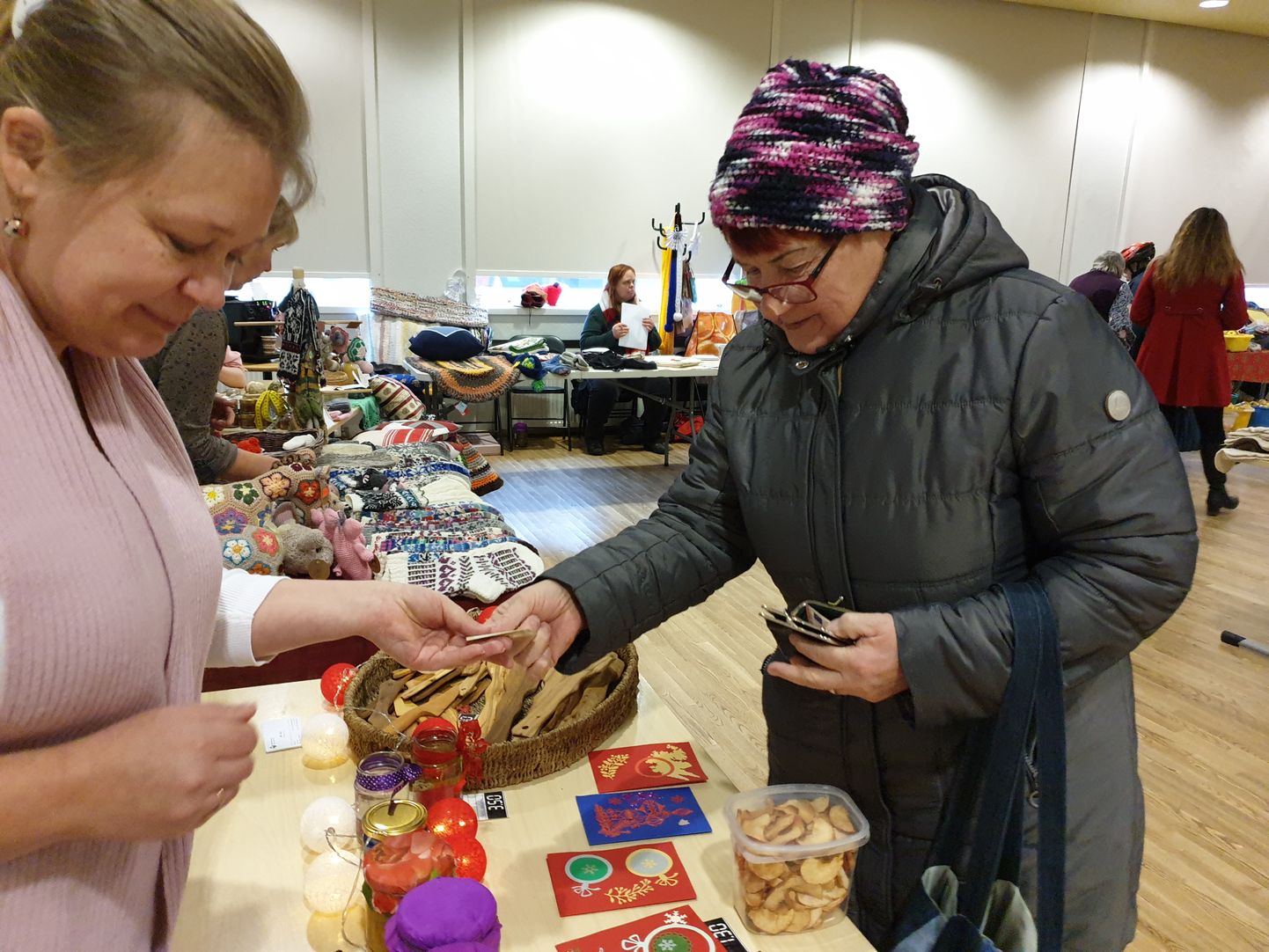 Laadaline Mari ulatab müüjale, Saaremaa diabeediseltsi juhile Ave Kaalule raha karbitäie õunakrõpsude eest.