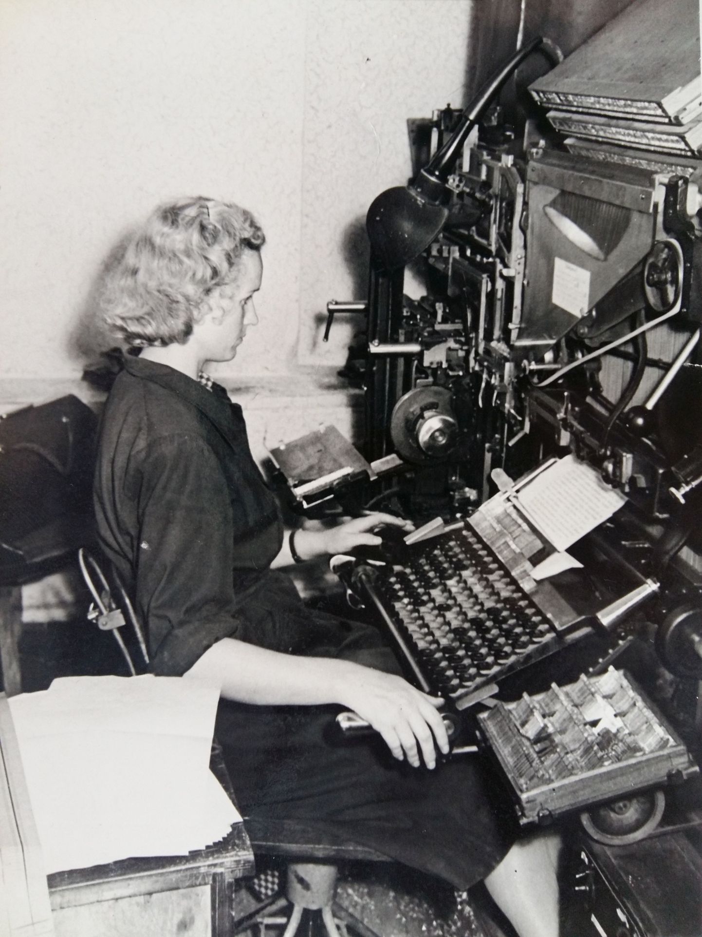 Laduja Niina Leesik tipib käsikirjast teksti klaviatuuri abil realadumismasinasse ehk linotüüpi, millest väljub ladu tähematriitside järgi trükitinast valatud ridadena.
