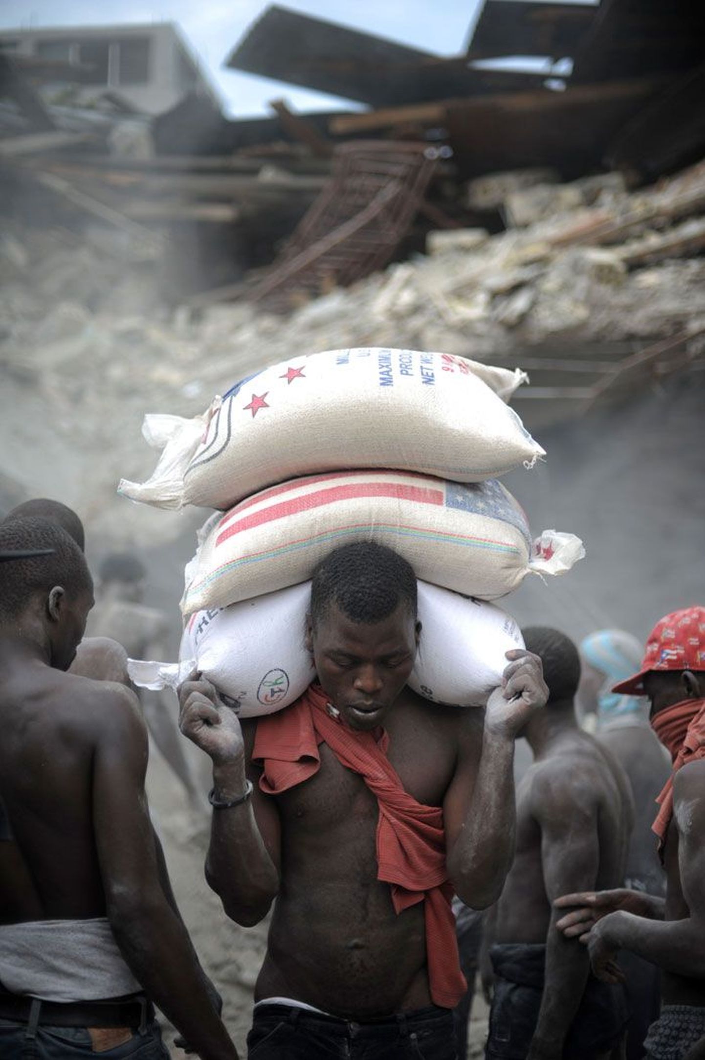 Ajutine tööline tassimas riisikotte Haiti pealinnas Port-au-Prince’is pärast maavärinat.