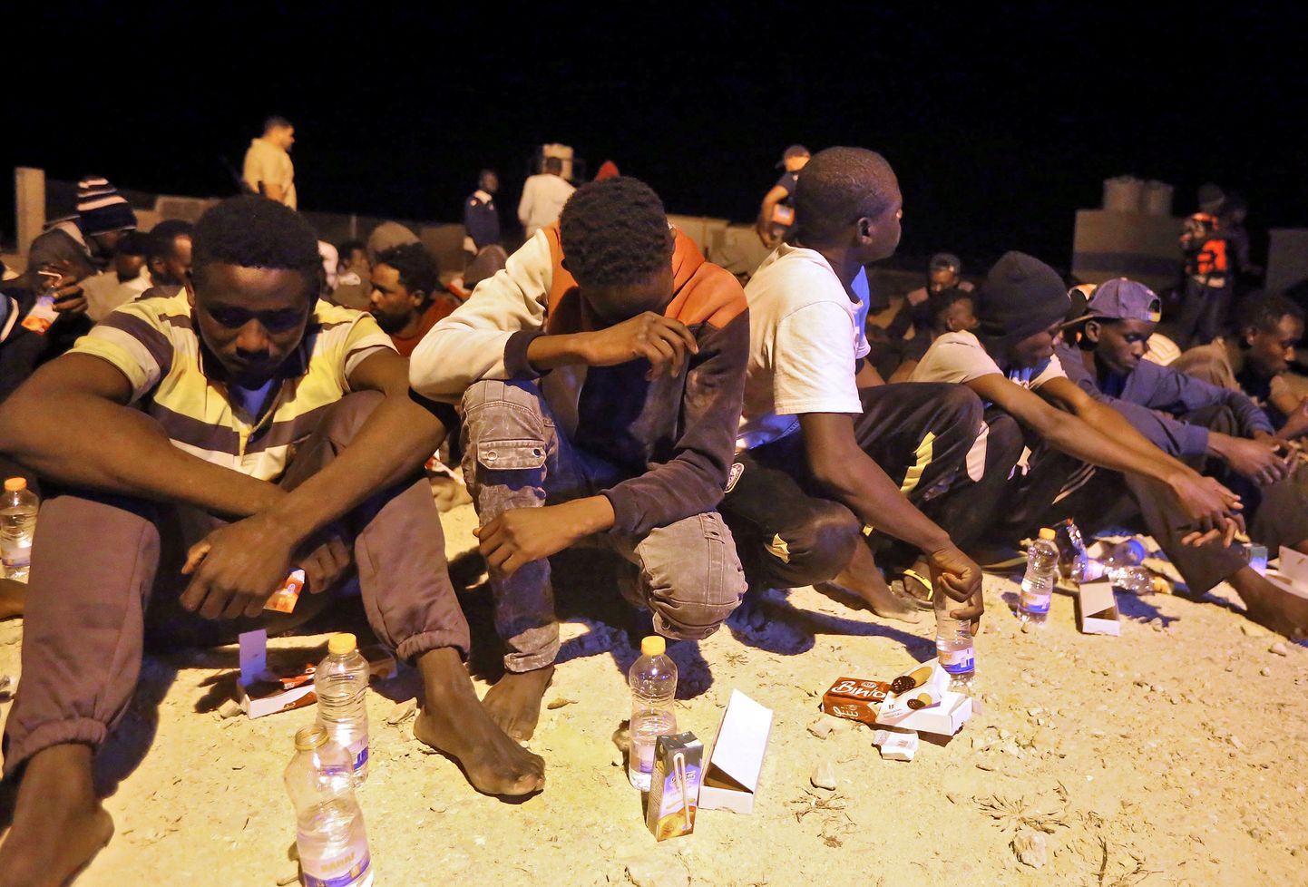 Vahemerelt päästetud Aafrika migrandid istuvad Liibüa rannikul.