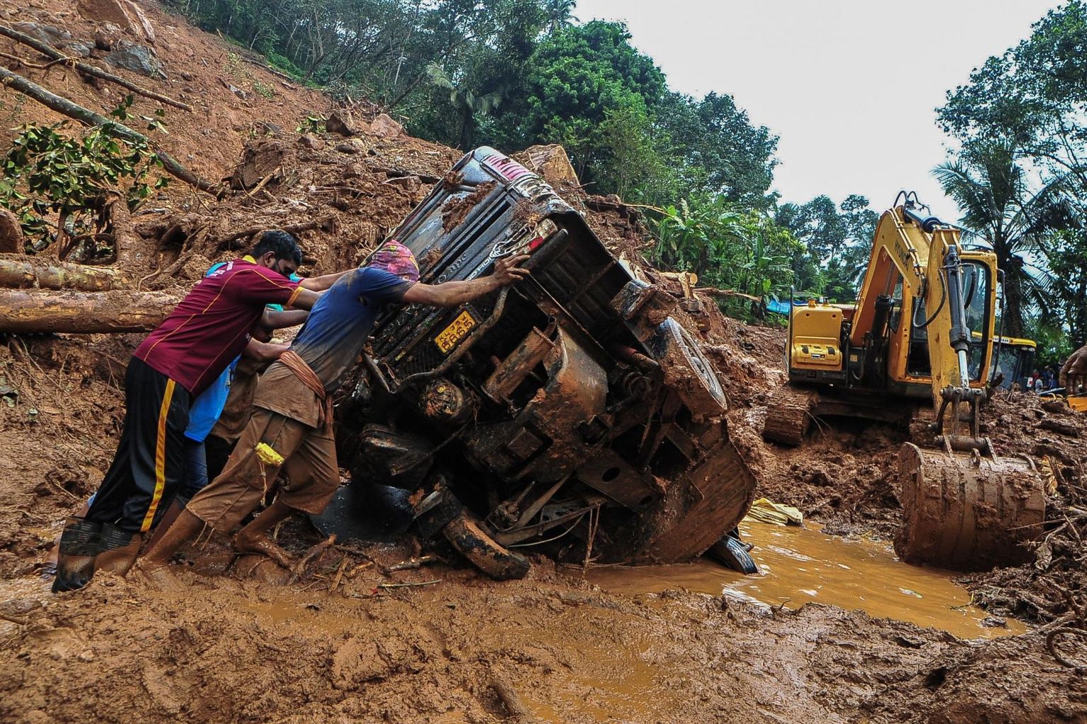 Päästajad lükkamas kummuli vajunud autot Kokkayari külas Kerala osariigis. 