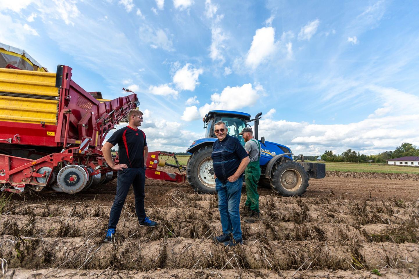 Peremees Mart Timmi (ees paremal) ja tootmisjuht Kristjan Runtal kartulikombainiga, mis suudab päevas korjata 250 tonni kartuleid. 