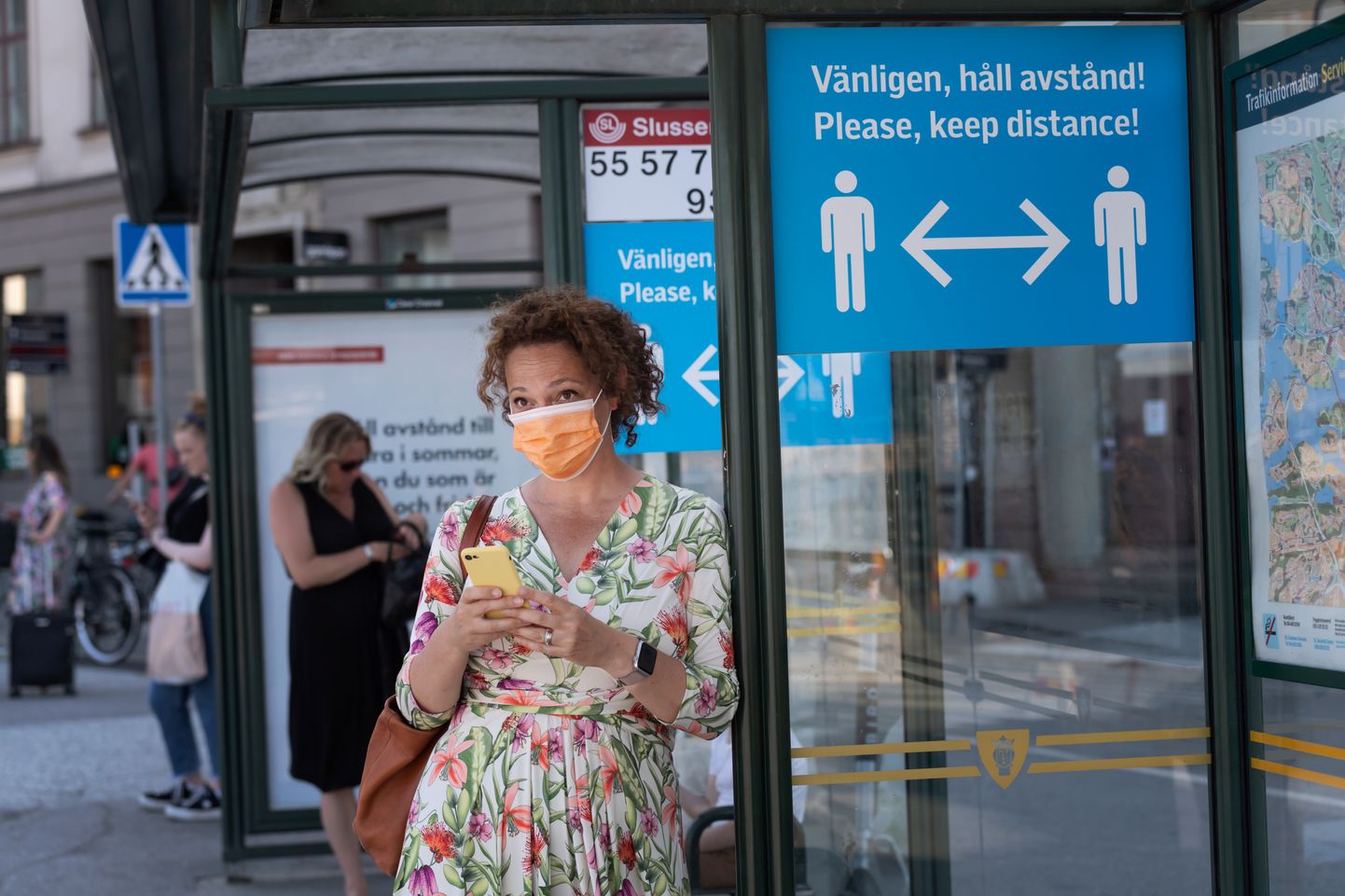 Näomaskis naine Rootsi pealinnas Stockholmis bussipeatuses, millele olev kiri palub inimestel hoida üksteisega distantsi.