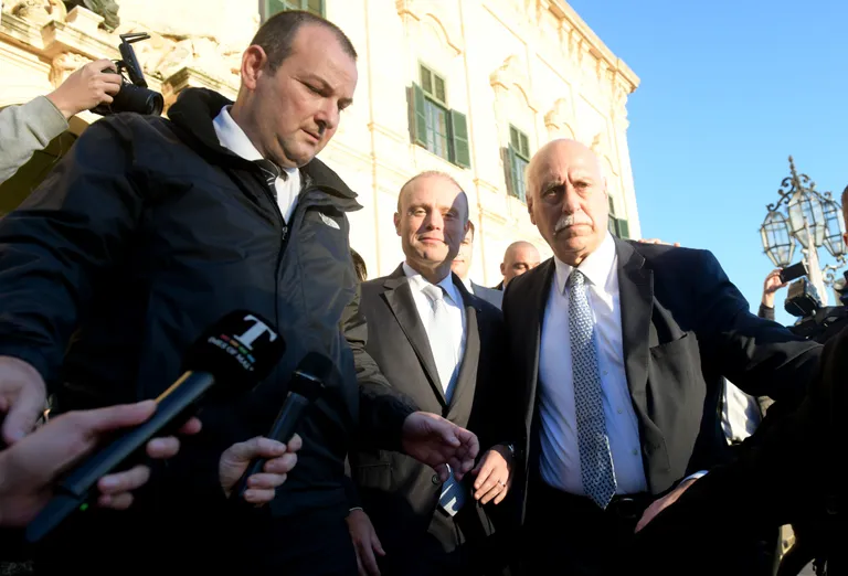 Malta peaminister Joseph Muscat (keskel) vajas eile parlamendist lahkudes enda kõrvale turvamehi, kes kaitsesid teda vihaste meeleavaldajate eest.