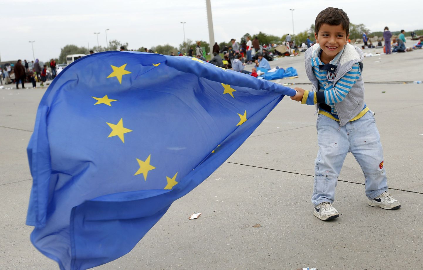 Юный мигрант играет с флагом ЕС. Иллюстративное фото.