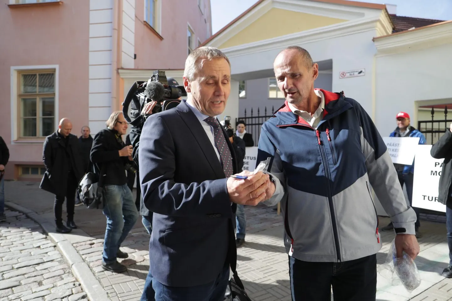 Pealinnas korraldatud piketil ainsana Lääne-Virumaa pritsimehi esindanud Aivar Lepp (paremal) jagas valitsuskabineti liikmetele päästjaid meenutavat nänni. Pildil võtab esemeid vastu kultuuriminister Tõnis Lukas.