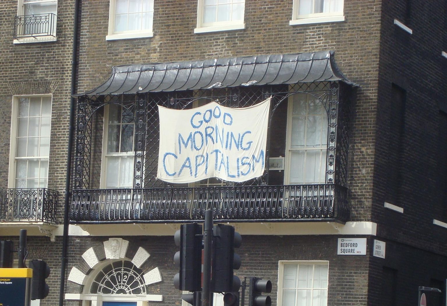 Loosung kirjaga «Tere hommikust, kapitalism!» Londonis Bedford Square-i kortermaja rõdul 2010. aasta kevadel.
