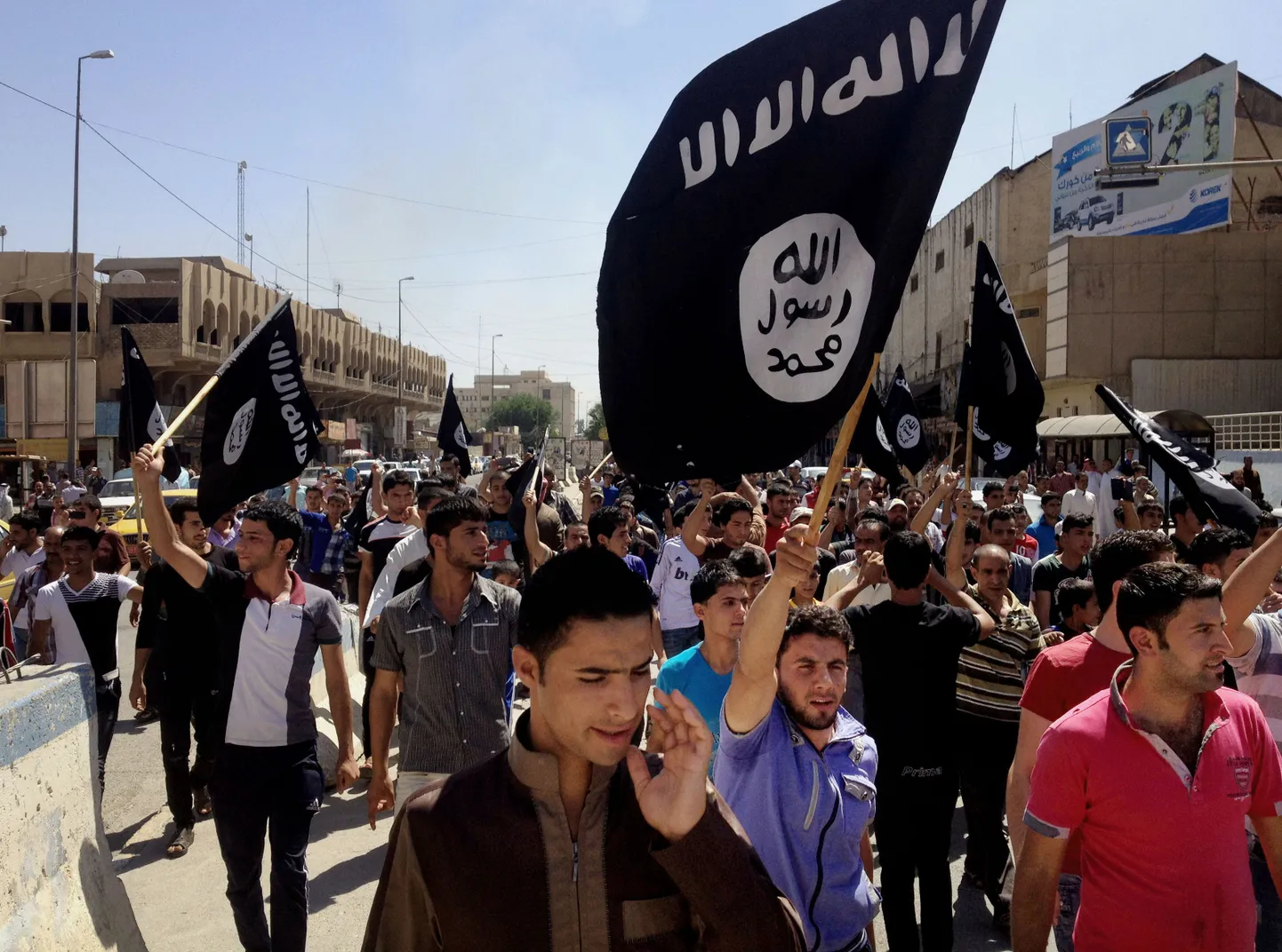 FILE - In this Monday, June 16, 2014 file photo, demonstrators chant pro-Islamic State group slogans as they wave the group's flags in front of the provincial government headquarters in Mosul, 225 miles (360 kilometers) northwest of Baghdad, Iraq. The IS declaration of a "caliphate" in Iraq and Syria inspired a stream of thousands of foreign fighters to join it and earned it pledges of allegiance by individual militants around the region. (AP Photo, File)