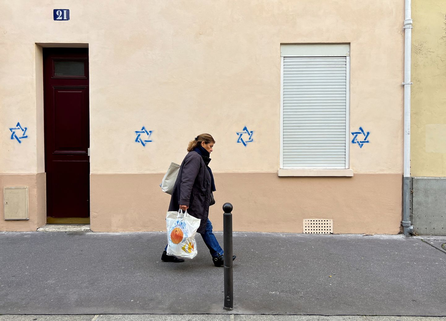 Naine möödub eile Pariisis majast, mille seinale on joonistatud Taaveti tähed.
