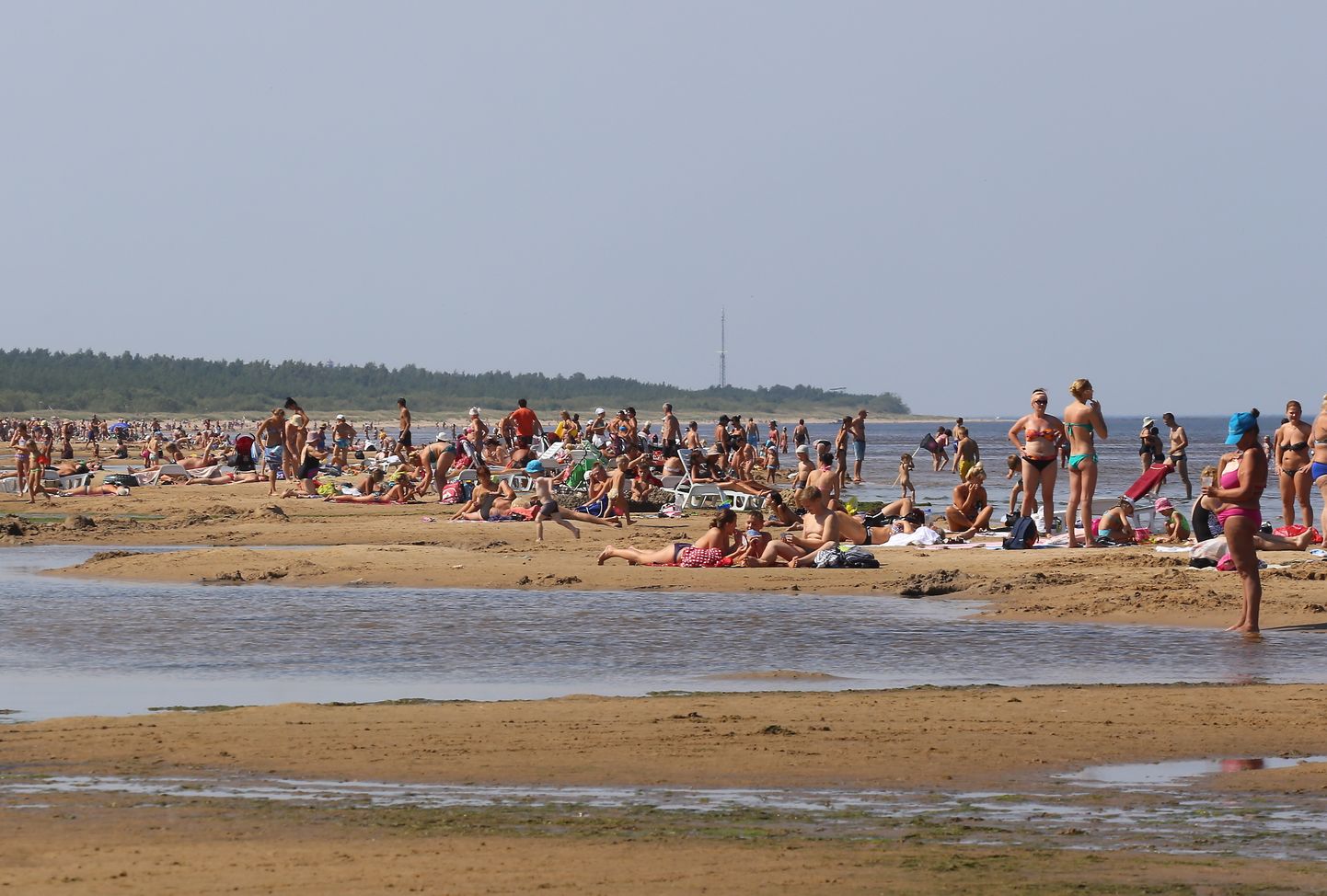 Cilvēki tveicīgajā vasaras dienā jūrmalā pie Mangaļsalas.
