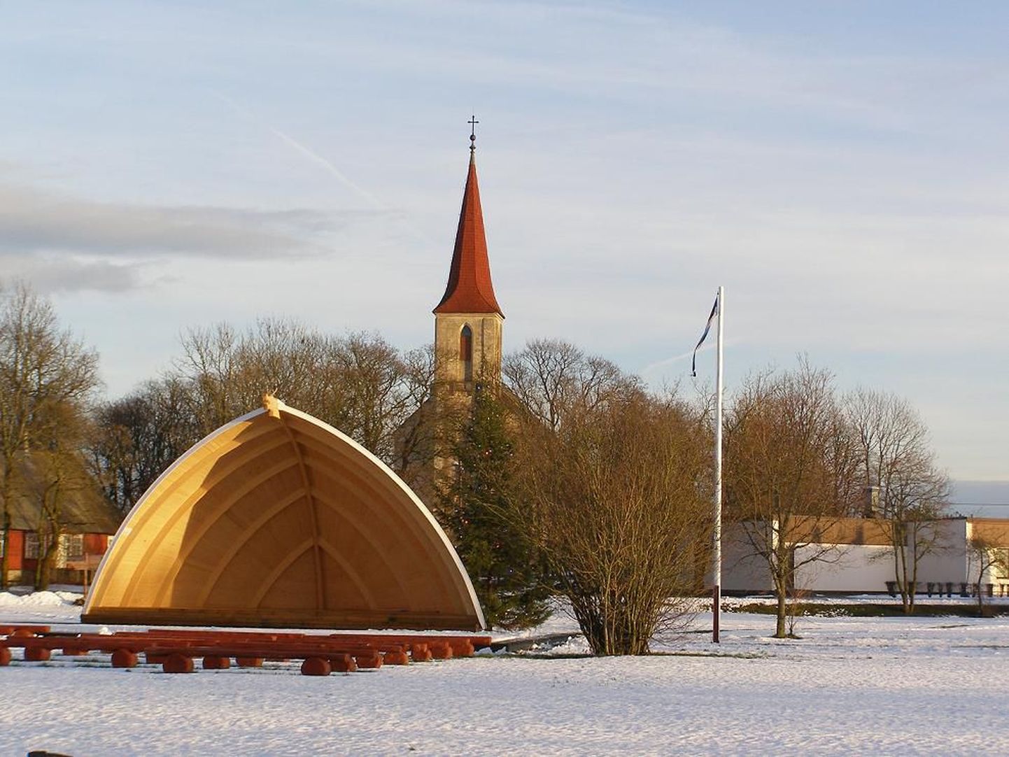 Saaremaa Mustjala külaplatsi lipumast, selleks sügiseks valminud laululava ja pärastlõunapäikeses jõulupuuga.