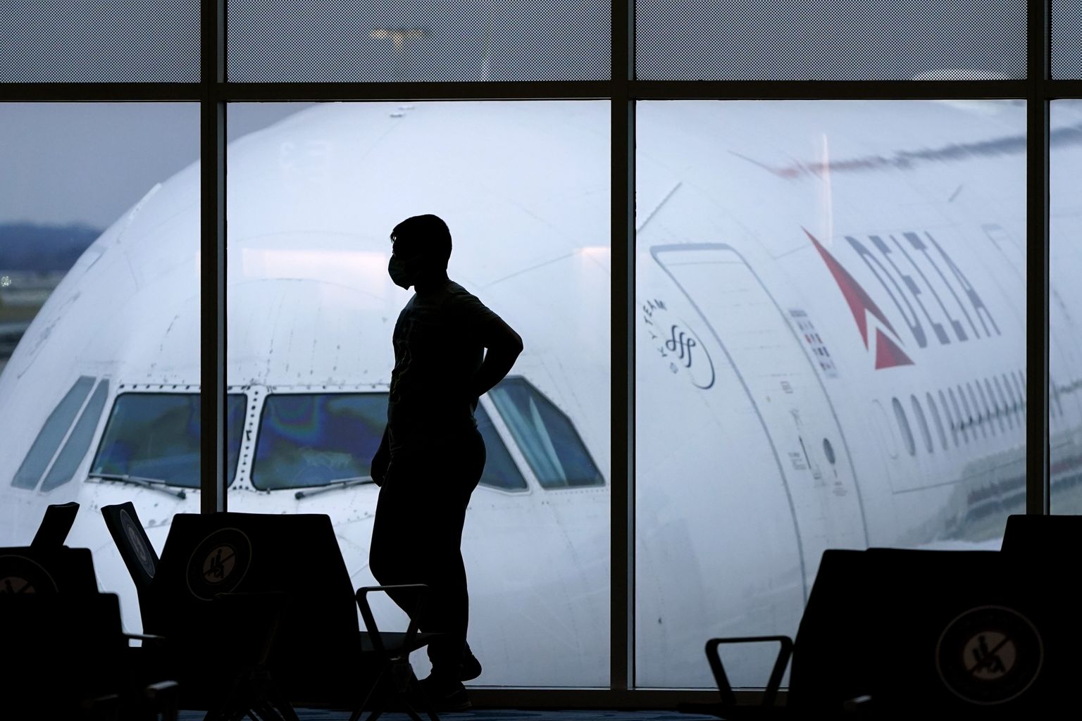 Reisija lennujaamas Delta Airlinesi lennuki taustal.