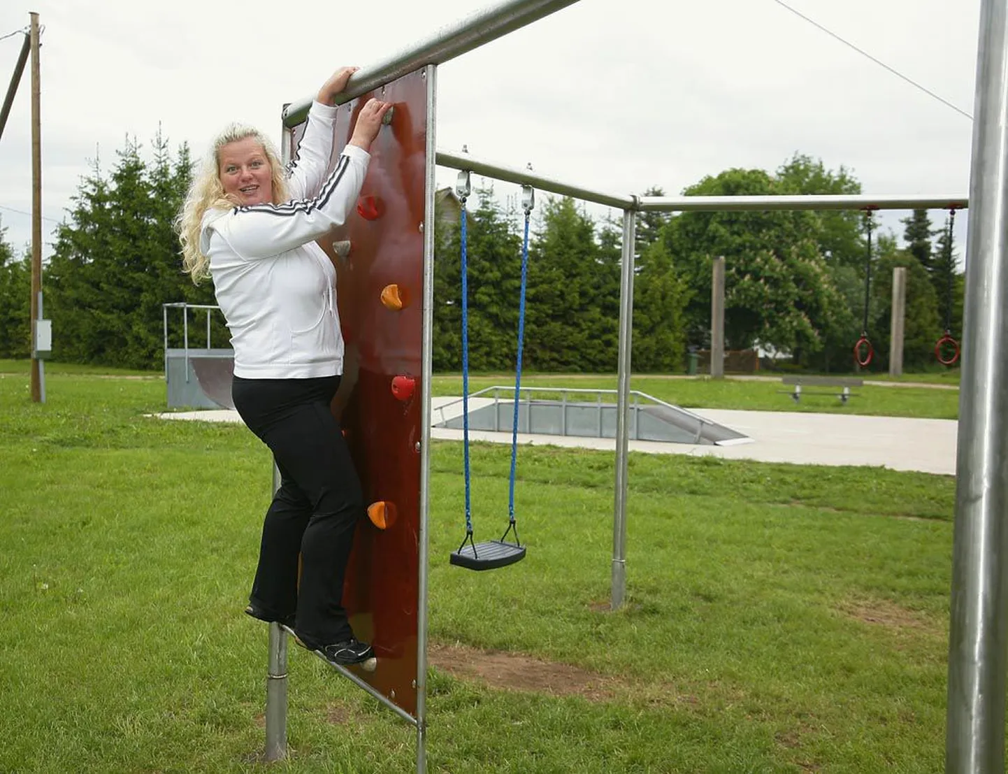 Lõpe klubi juhataja Kristel Rohumägi näitab ronimisseina, taamal paistab rulapark.