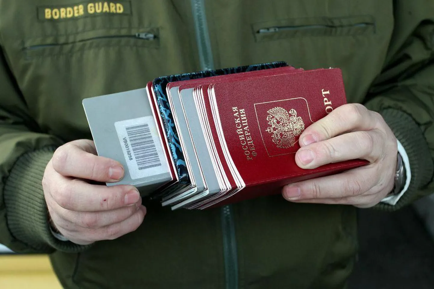 Hallid passid ja Venemaa passid Narva piiripunktis piirivalvuri näppude vahel. Enamikul Narva ja Ivangorodi vahel käijatest on just selline dokument.