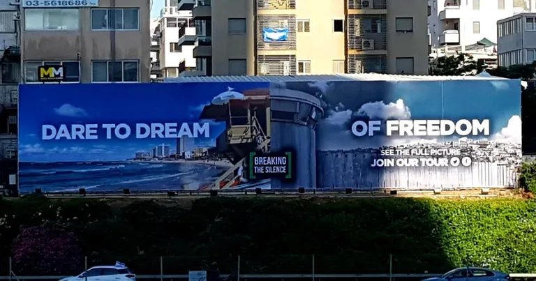 Palestiina aktivistide püstitatud plakati vasakul küljel on näha pilti rannikulinnast Tel Avivist, paremal pool aga on pilt viitega Iisraeli okupatsioonile. Plakatil on kiri «Julge unistada vabadusest».