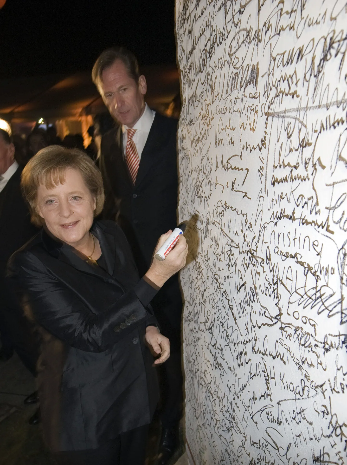 Saksamaa kantsler Angela Merkel kirjutamas oma allkirja Berliini müüri lõigule Glienicker silla muuseumi avamisel 2009. aastal.