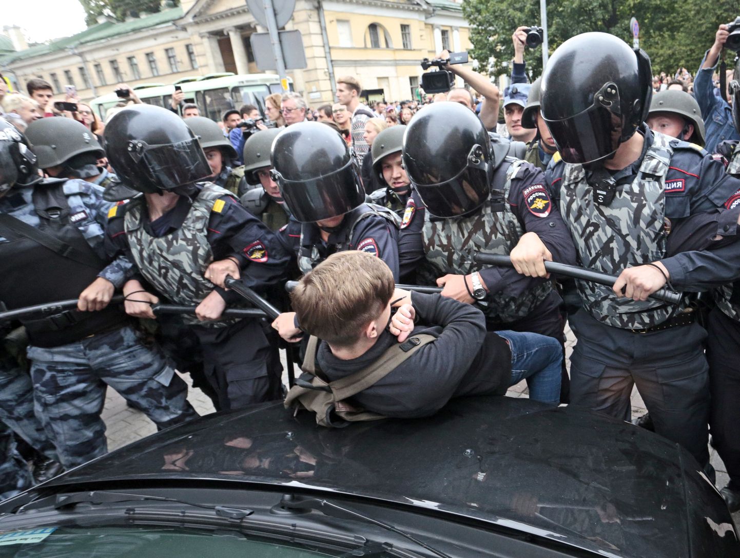 Vene politseinikud lükkamas teismelist protestijat.