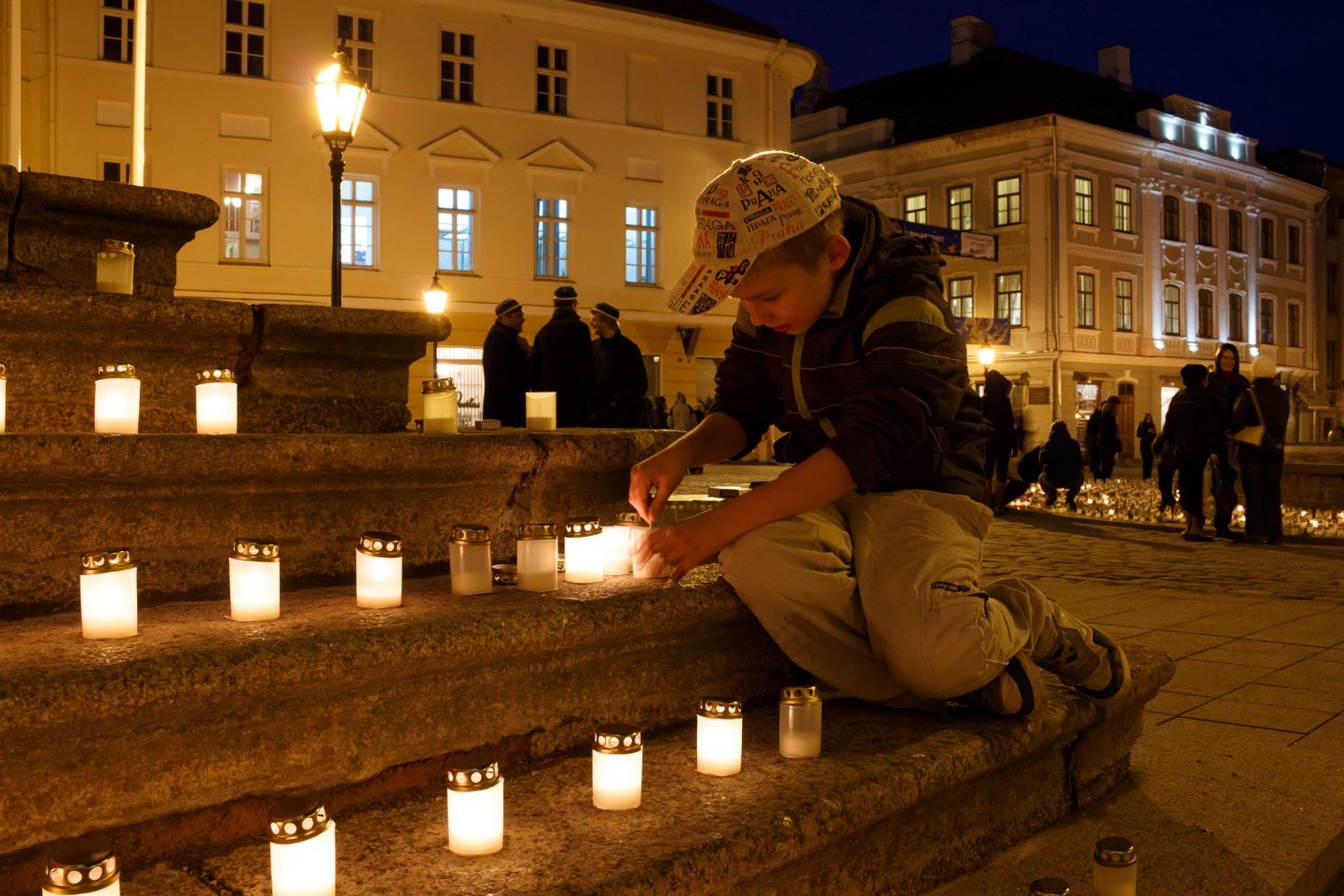 Noor poiss süütab Tartu Linnavalitsuse trepil küünlaid küüditatute mälestuseks.