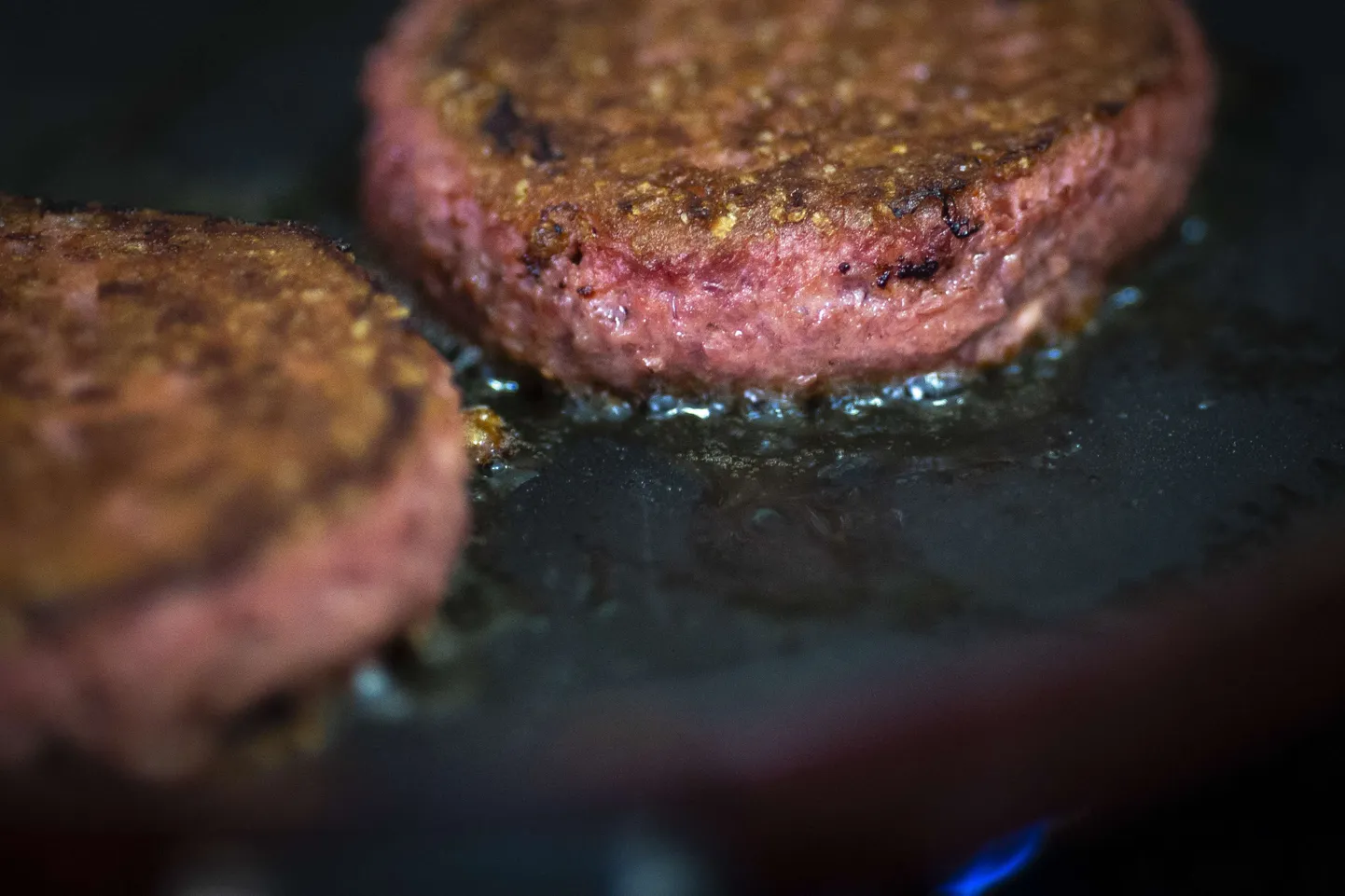Kaks taimset burgerit küpsevad pannil.