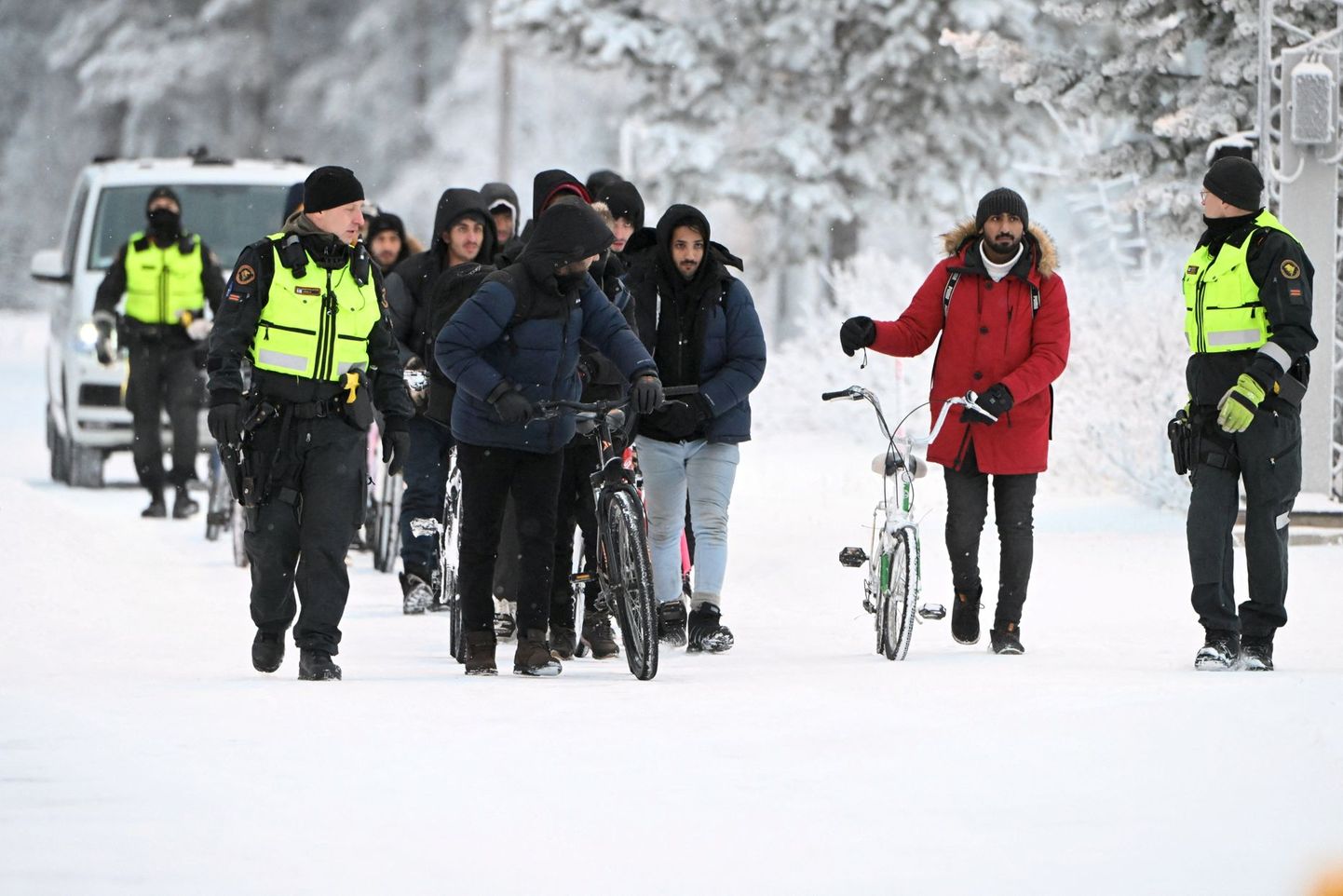 Финские пограничники эскортируют группу нелегалов на погранпункте Салла.