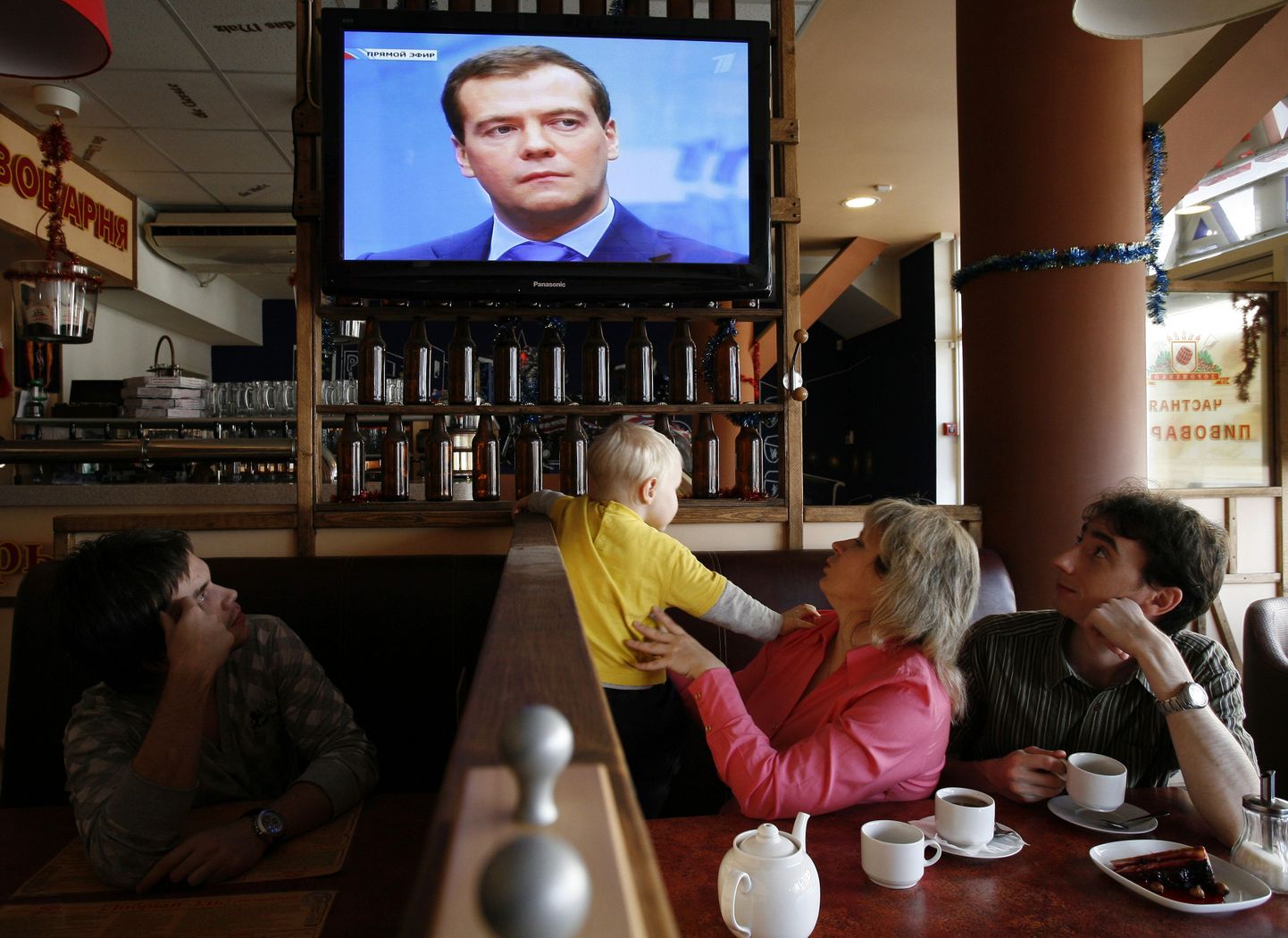 Посетители кафе слушают телевыступление Медведева 24 декабря.