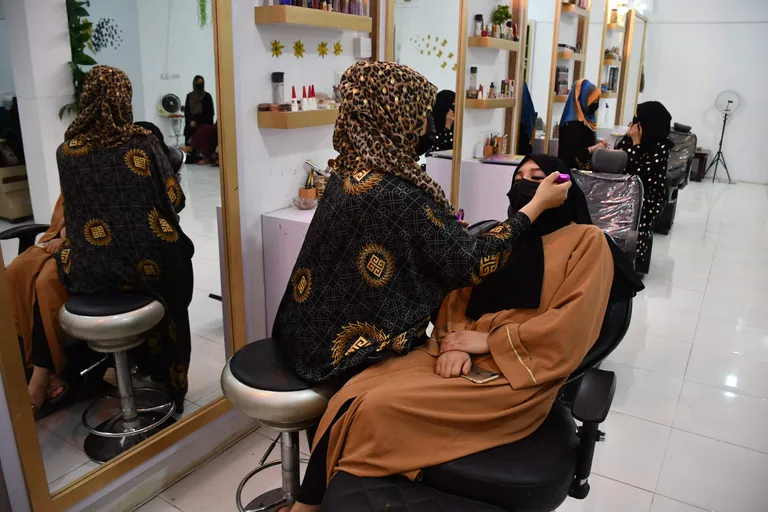 Grima māksliniece salonā Mazārešarīfā 2023.gada 5.jūlijā uzklāj kosmētiku klientei - mēnesi pirms spēkā stājās skaistumkopšanas salonu aizliegums