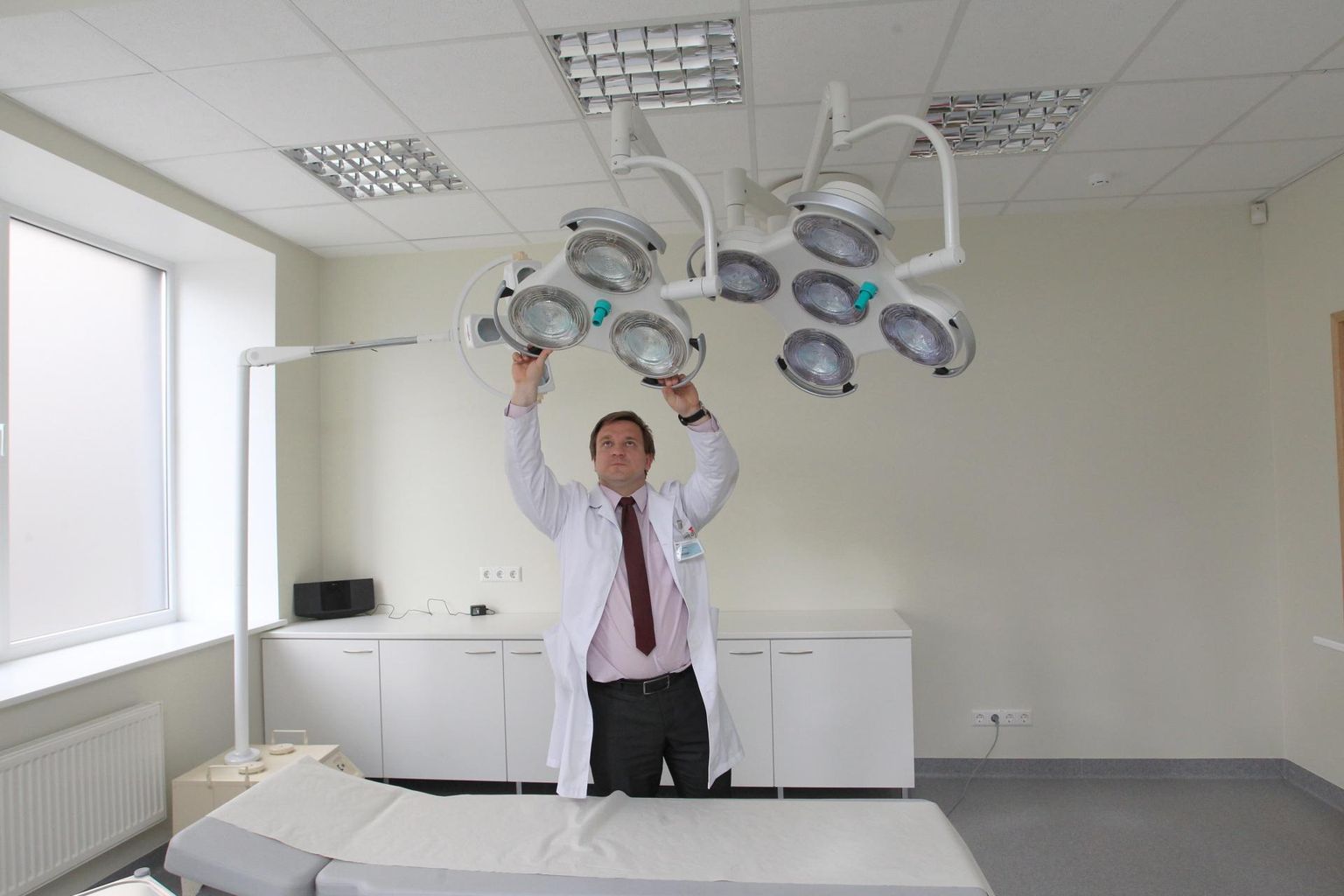 Pildil sätib Kristo Ausmees oma laienenud Medita kliiniku protseduuriruumis lampi.