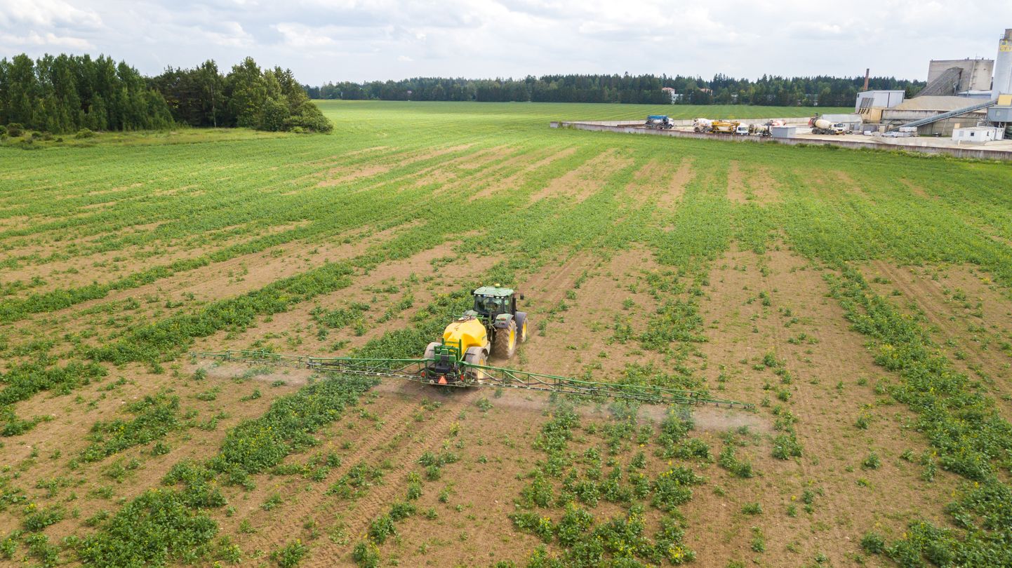 Traktor pihustab põllul. Foto on illustreeriv.