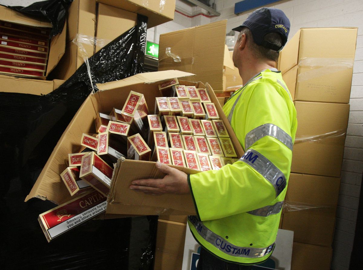 Tаможенный чиновник сортирует контрабандные сигареты в ирландском порту.