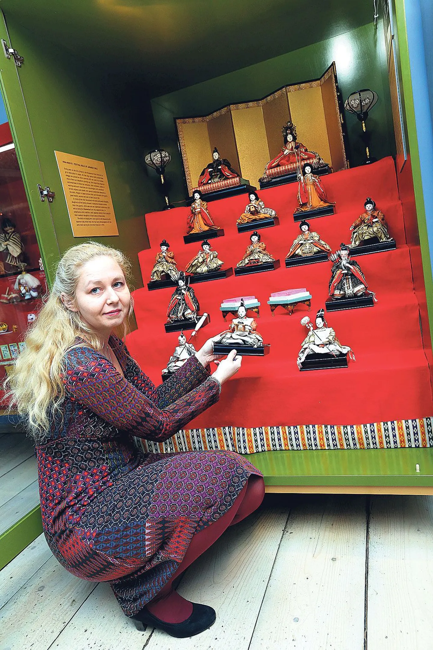 Tartu mänguasjamuuseumi direktor Triin Vaaro tutvustab vitriinkappi paigutatud Jaapani nukke – keisrit ja keisrinnat ning nende õukonna liikmeid. Käes hoiab ta üht ministrit.