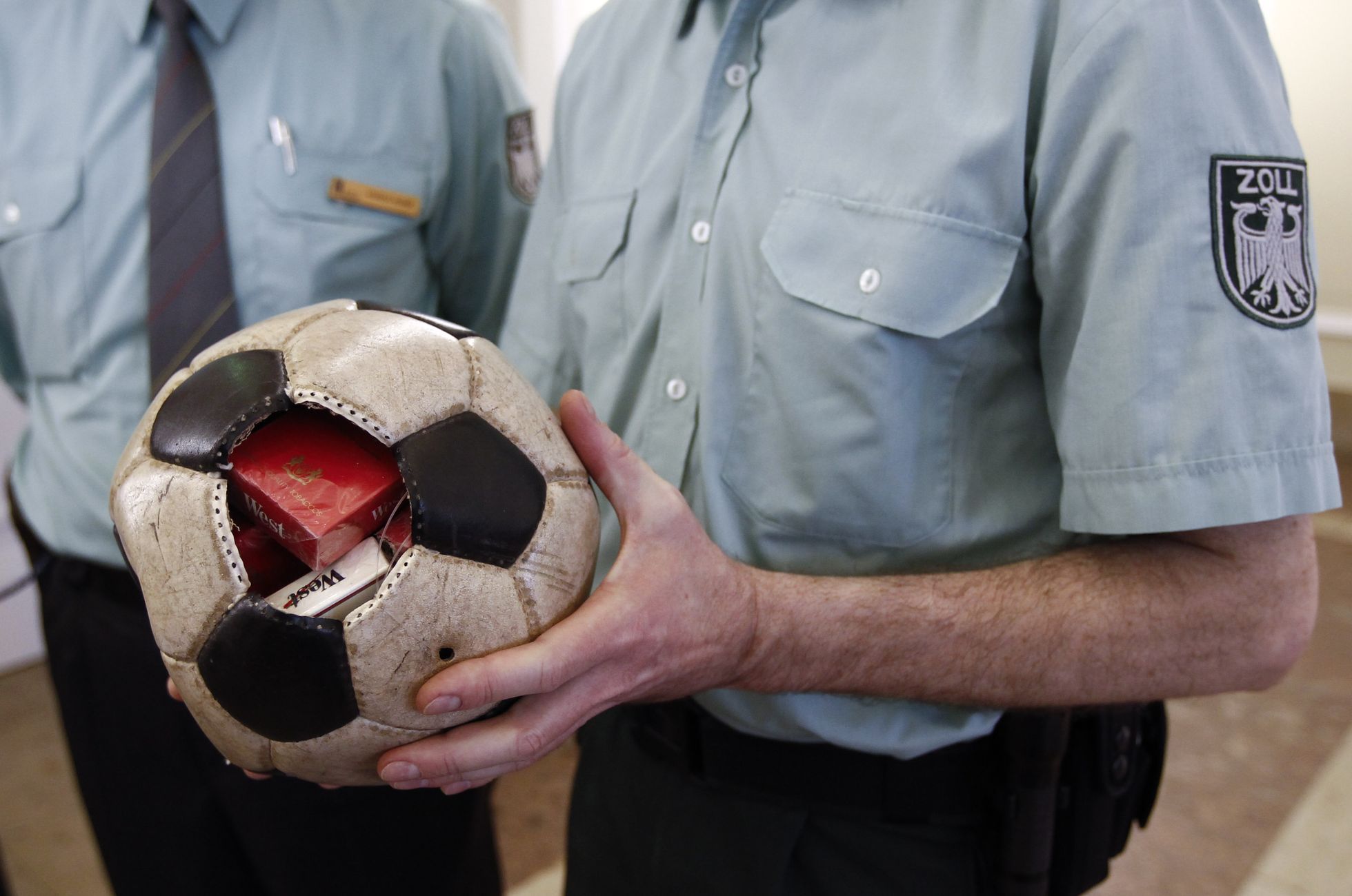 Немецкий таможенник демонстрирует футбольный мяч, использовавшийся как тайник для контрабанды сигарет.
