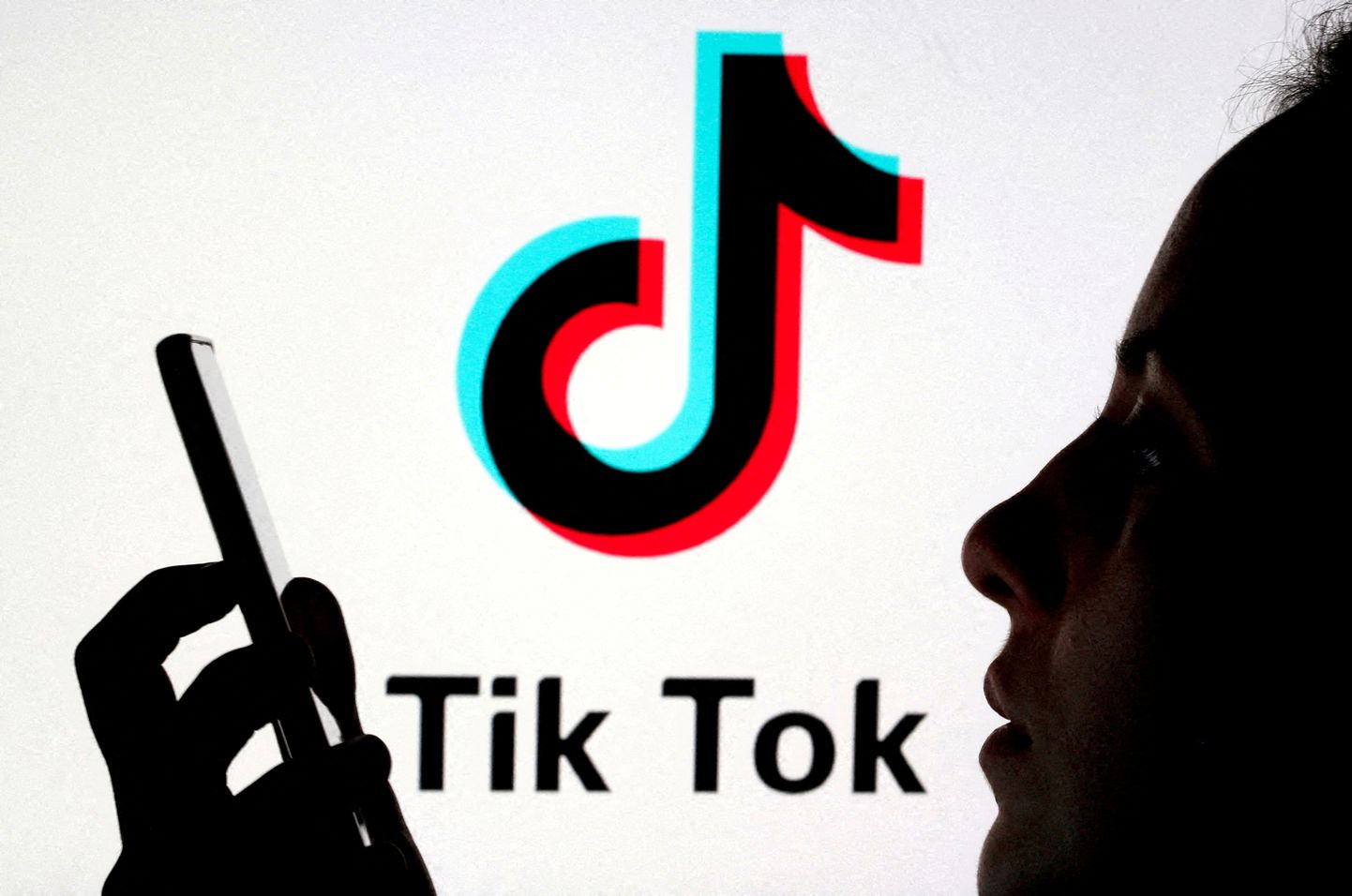 Naine nutitelefoniga TikToki logo ees.