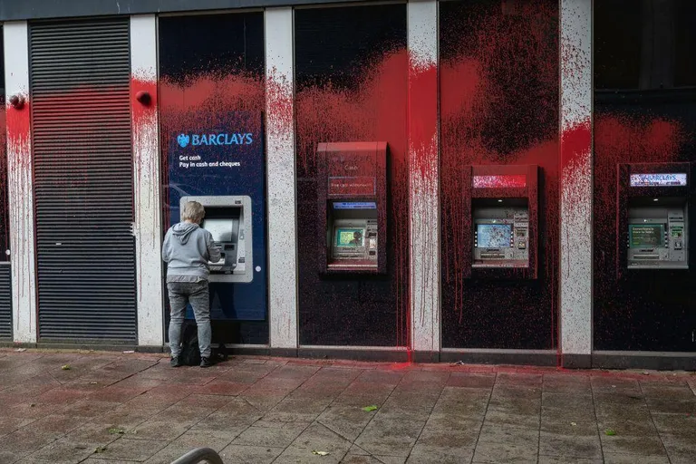 Человек у банкомата, замазанного красной краской