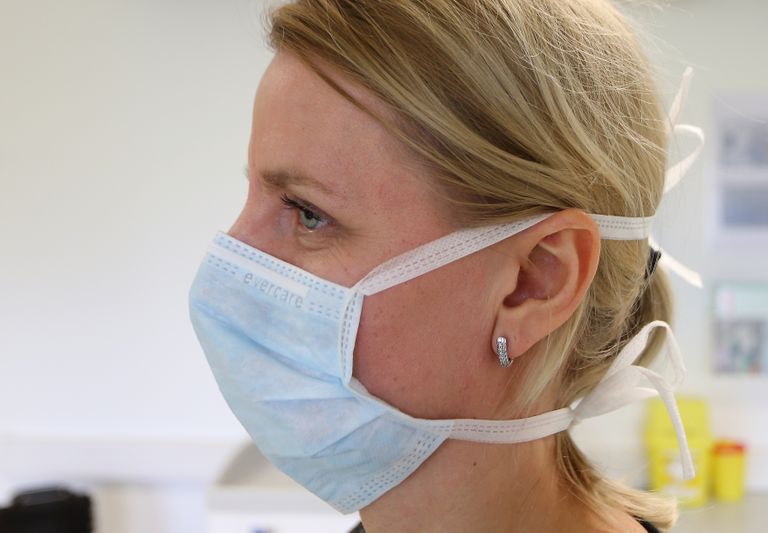 Õde Marit Kiljako näitab, kuidas on tark paeltega maski kinni siduda, et see näo ees tihedalt istuks.