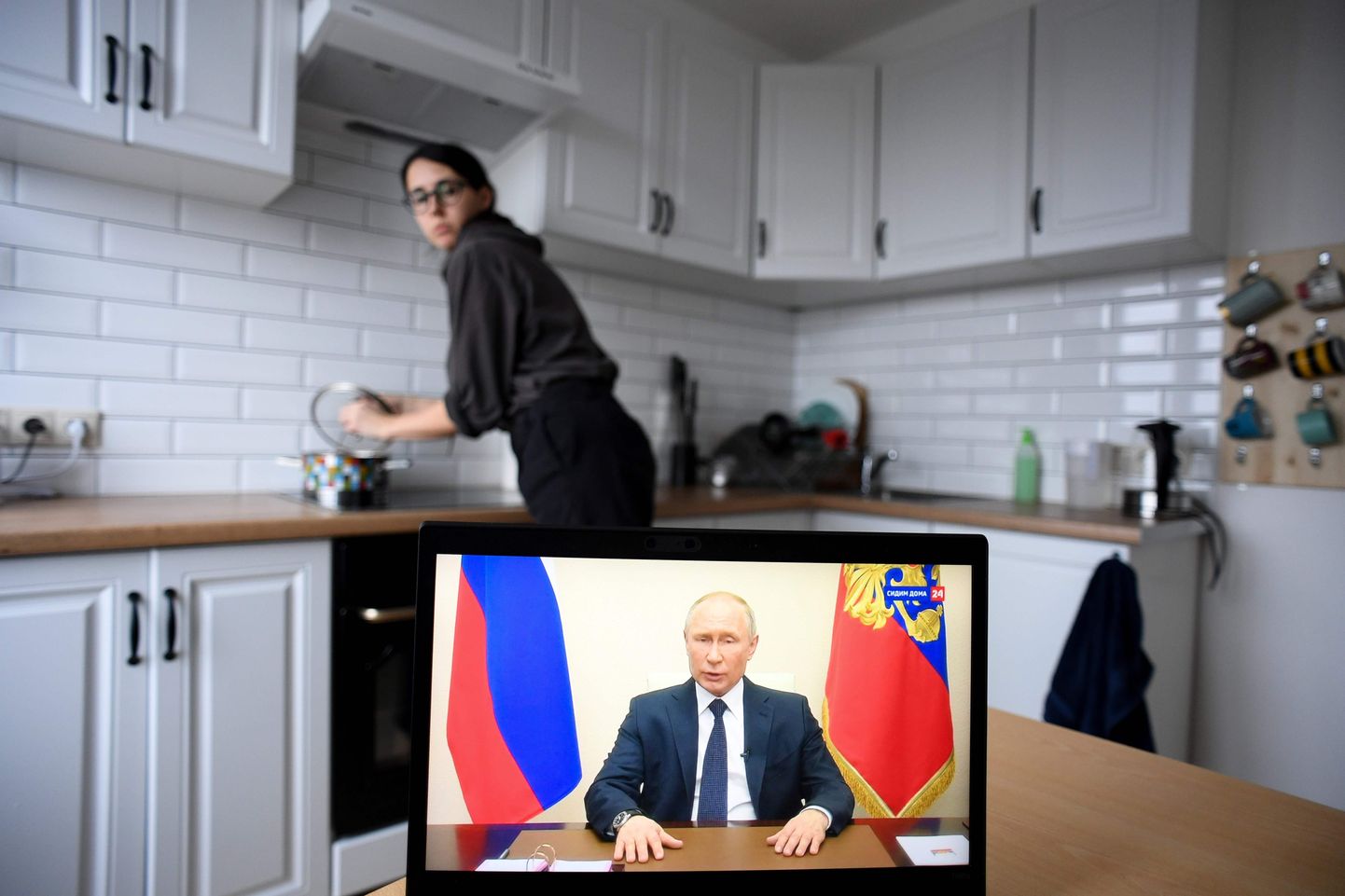 Venelanna jälgib toitu valmistades president Putini pöördumist.