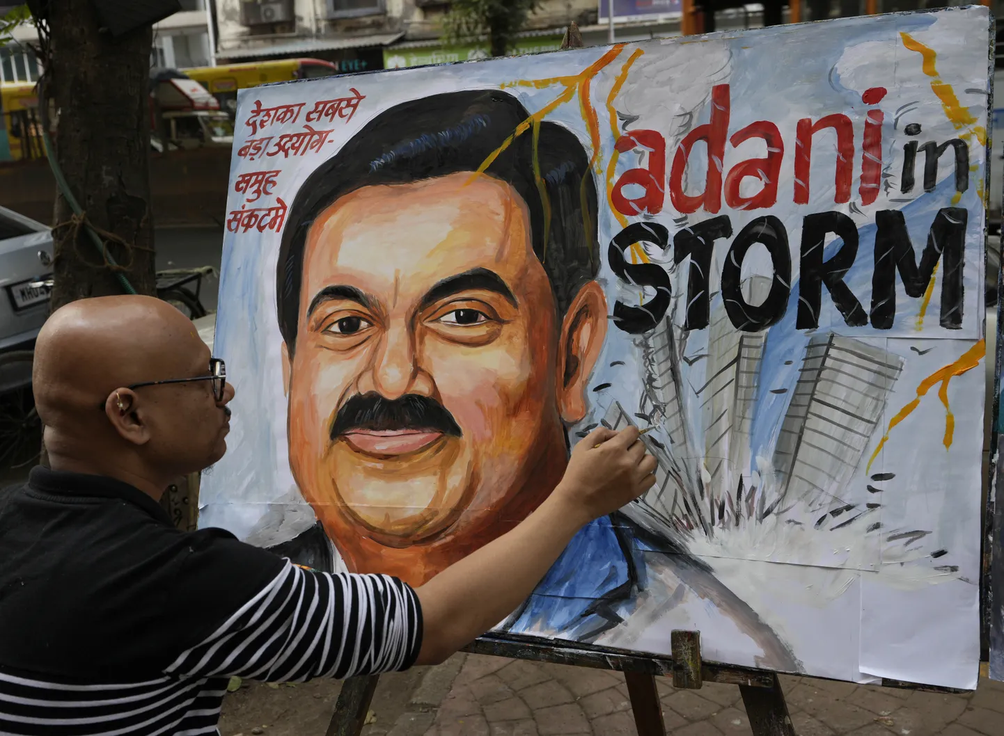 Kunstnik ja kooliõpetaja Sagar Kambli annab 3. veebruaril 2023 Indias Mumbais viimase lihvi India ärimehe Gautam Adani maalile, mis kujutab Adani grupi aktsialangusest tingitud jätkuvat kriisi. (AP Photo/Rajanish Kakade)  RKD102