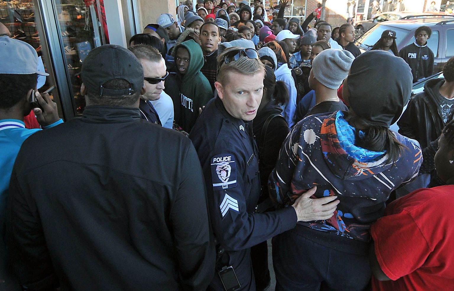 Politseinik rahustab  järjekorras olevaid inimesi, kes soovivad osta Air Jordan 11 Retro Concords tosse.