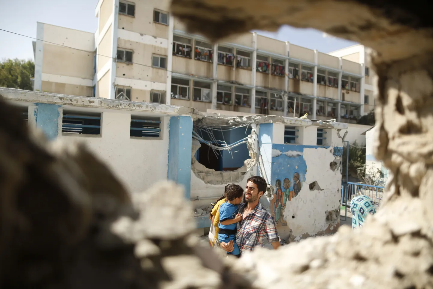 Palestiinlane kannab poissi läbi purustatud klassiruumi ÜRO poolt juhitud kooli.