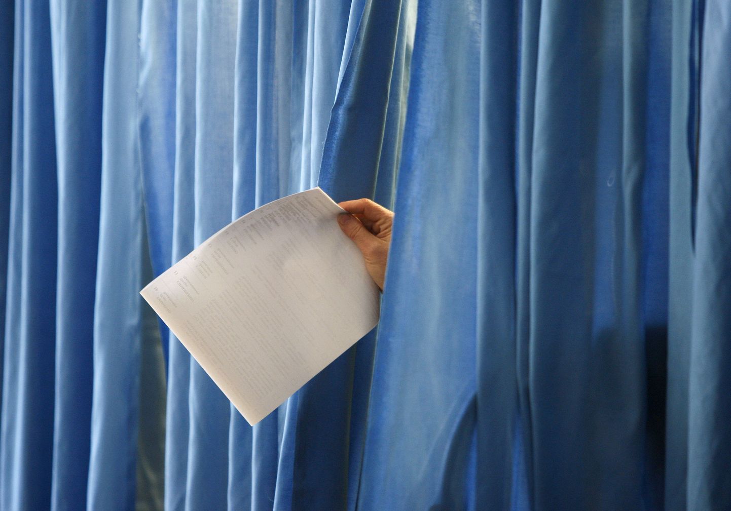 Hääletuskabiini eesriiete vahelt paistab naisterahva käsi. Pilt on tehtud Dnipropetrovskis.